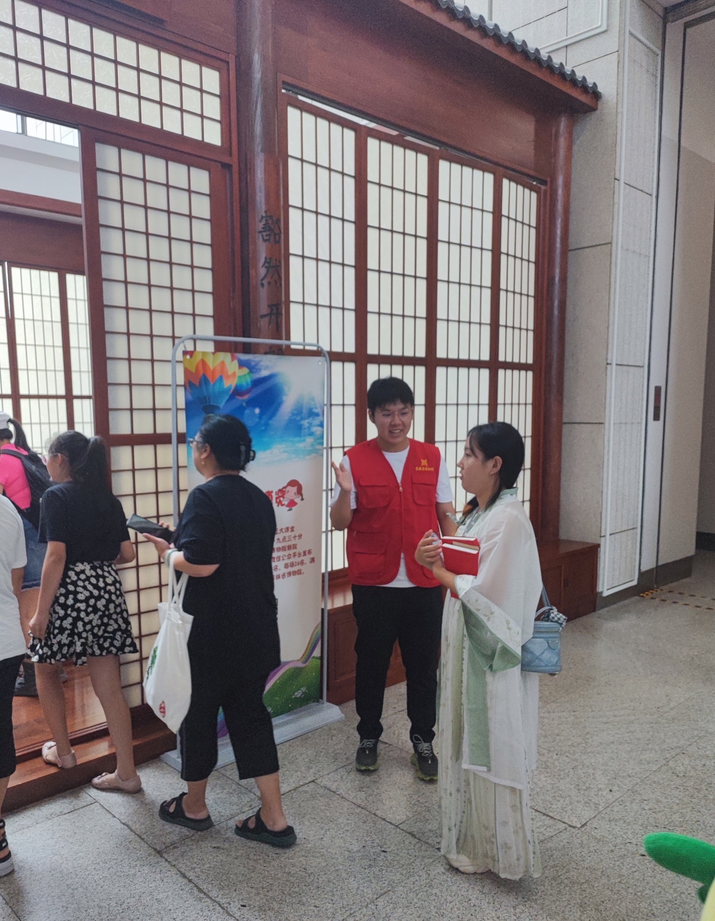 Talking with visitors in a red museum volunteer vest